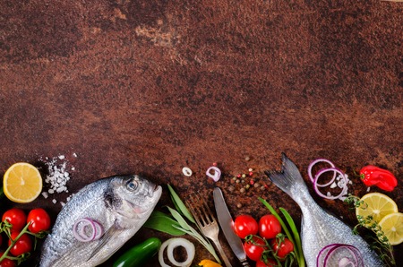 Fresh raw fish with lemon, herbs, onion, paprika, cherry tomatoes, onion, salt on rustic background....