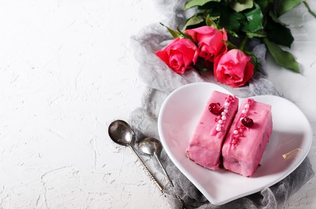 Valentine pink cakes and two teaspoons on white concrete background. Free space for your textの写真素材