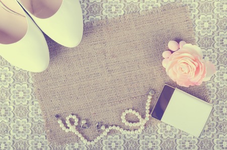 Women's wedding accessories. Bride's morning. White shoes, perfume, pearl necklace and earrings on white lace cloth and sackcloth, canvas.の写真素材