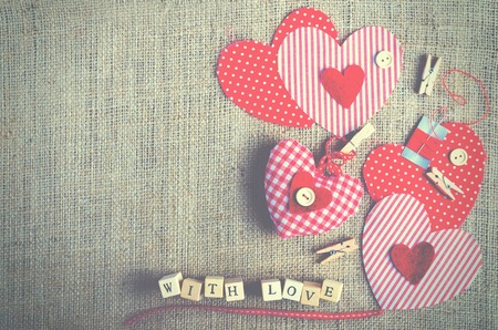 Red polka dot textile hearts on burlap. Free space for your textの写真素材