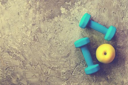 Two blue weights, dumbbells and yellow apple on concrete backgroundの写真素材