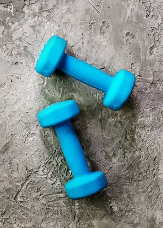 Old dumbbells with measuring tape and yellow apple on concrete background. Free space for your text. Sport concept.の写真素材