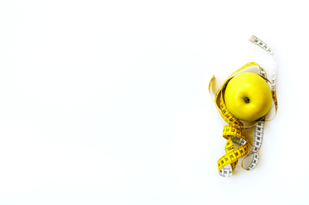 Measuring tape wrapped around fresh tasty yellow apple isolated on white background. Diet, weight loss, fitness, sport concept. Spring and summer fruit. Copy space. Bannerの写真素材