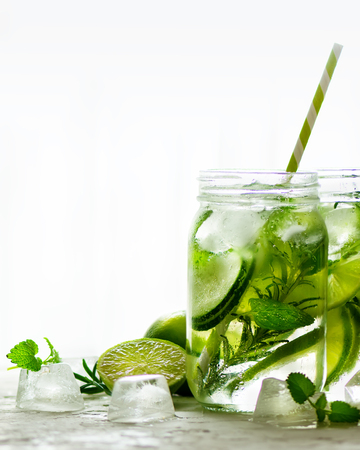 Cold and refreshing detox water with lime, cucumber, rosemary and ice in glass jar. Copyspaceの写真素材