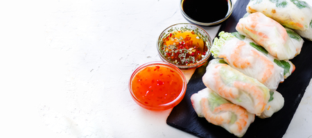 Vietnamese spring rolls - rice paper, lettuce, salad, vermicelli, noodles, shrimps, fish sauce, sweet chili, soy, lemon, veletables. Copy space. Asian and thai food. Traditional national cuisineの写真素材