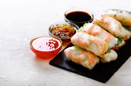 Vietnamese spring rolls - rice paper, lettuce, salad, vermicelli, noodles, shrimps, fish sauce, sweet chili, soy, lemon, veletables. Copy space. Asian and thai food. Traditional national cuisineの写真素材