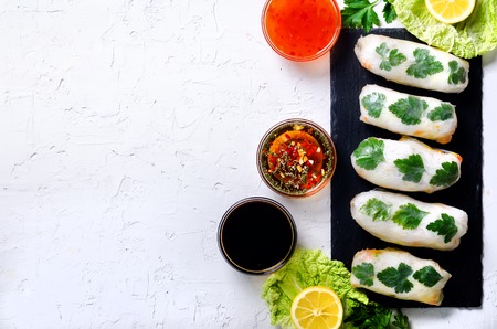 Fresh Vietnamese, Asian, Chinese food frame on white concrete background. Spring rolls rice paper,...