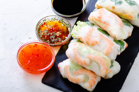 Vietnamese spring rolls - rice paper, lettuce, salad, vermicelli, noodles, shrimps, fish sauce, sweet chili, soy, lemon, veletables. Copy space. Asian and thai food. Traditional national cuisineの写真素材