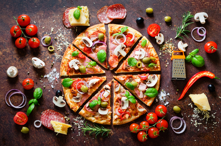 Food ingredients and spices for cooking delicious italian pizza. Mushrooms, tomatoes, cheese, onion, oil, pepper, salt, basil, grater, olive on rustic background. Copyspace. Top viewの写真素材