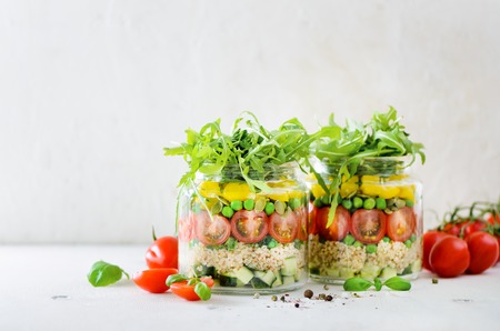 Healthy salad jar with quinoa and vegetables, cherry tomatoes, cucumber, ruccola. Raw vegetarian meal for diet, detox, clean eating. Homemade concept.の写真素材