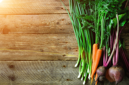 Fresh vegetables - carrots, beetroots, green onion on wooden background. Harvest. Concept of diet, raw, vegetarian meal.の写真素材