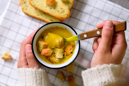 Cup with carrot cream soup in girl hands on light background with copy space for your textの写真素材