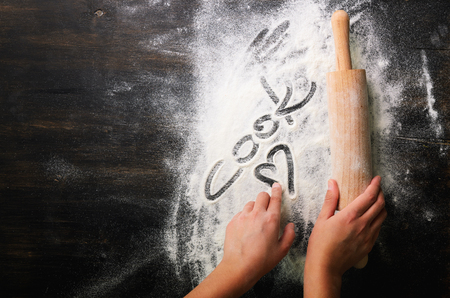Baking background. Heart of flour, text Cook and rolling pin on dark table with copy space, top viewの写真素材