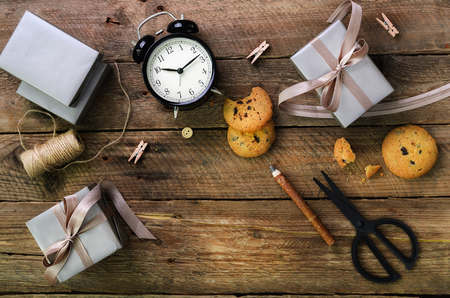Gift boxes, black alarm clock, pen, scissors on wooden background. Preparing for birthday, christmas, new year.の写真素材