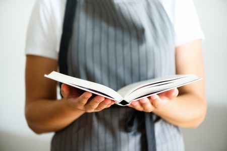 Girl wearing grey apron and reading book. Lifestyle conceptの写真素材