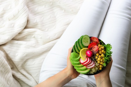 Girl holds in hands vegan, detox raw buddha bowl with avocado, quinoa, cucumber, radish, salad,...