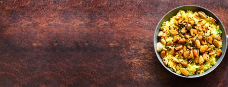 Traditional spanish seafood paella in pan rice, peas, shrimps, mussels, squid on rustic dark background. Top view, copyspaceの写真素材