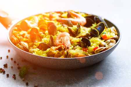Traditional spanish seafood paella in pan rice, peas, shrimps, mussels, squid on light grey concrete background. Top view, copyspaceの写真素材