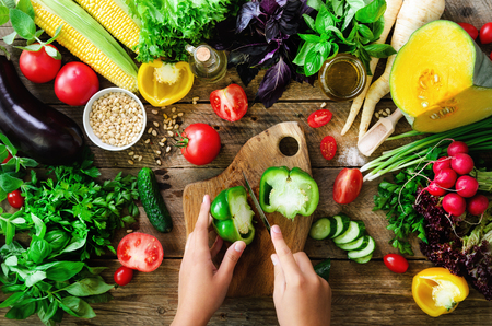 Woman hands cutting vegetables on wooden background. Vegetables cooking ingredients, top view, copy space, flat layの写真素材