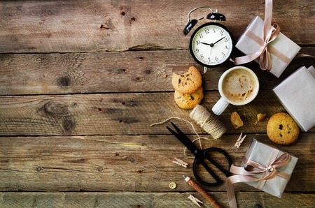 Gift boxes, black alarm clock, pen, scissors on wooden background. Preparing for birthday, christmas, new year.の写真素材