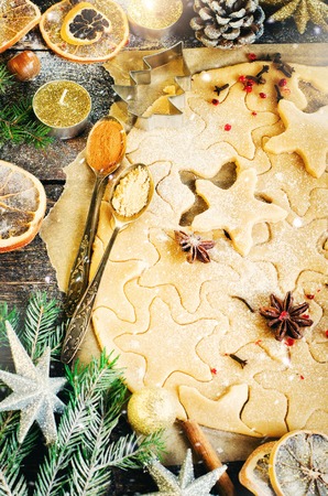 Ginger Bread Cookies. Christmas background with gifts, candle, cones, cinnamon sticks, dry orange, green tree fir branch, dough, rolling pin. Copy space.の写真素材