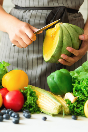 Woman peeling pumpking, vegetables, onion, tomatoes, corn, bell pepper, spinach, lettuce leaves. Clean eating, detox conceptの写真素材