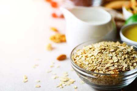 Organic ingredients for healthy breakfast - berries, milk, egg, oatmeal on grey concrete background. Copy space. Healthy breakfast concept. Sunny morningの写真素材