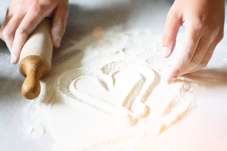 Heart of flour. Baking background with rolling pin, eggs, milk, butter on white kitchen table. Valentines day cooking, love concept.の写真素材