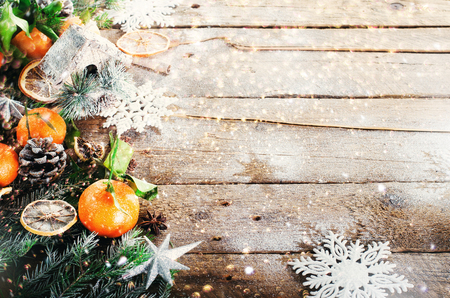 Magic Christmas background - vintage wood, candy cane, house, cinnamon, star anise, sweet mandarins with green leaves, cones, snowflakes. New Year. Top view, copy space, snow, bokeh.の写真素材