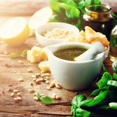 Ingredients for homemade pesto - basil, lemon, parmesan, pine nuts, garlic, olive oil and salt on rustic wooden background. Top view, flat lay, copyspace. Banner. Square cropの写真素材