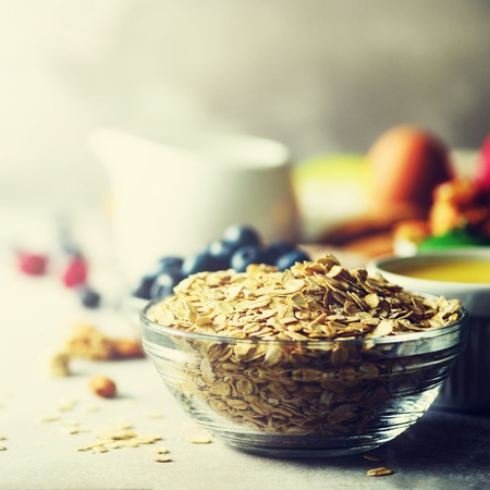 Organic ingredients for healthy breakfast - berries, milk, egg, oatmeal on grey concrete background. Copy space. Healthy breakfast concept. Square crop.の写真素材