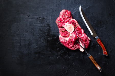 Raw fresh meat steak with cherry tomatoes, hot pepper, garlic, oil and herbs on dark stone, concrete background. Bannerの写真素材