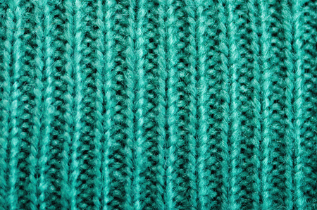 Knitted texture. Pattern fabric made of wool. Turquoise background, copy space.