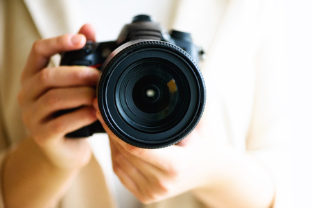 Girl hands holding photo camera, white background, copy space. Travel and shoot concept.の写真素材