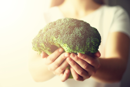 Woman in white T-shirt holding broccoli in hands. Copy space.の写真素材