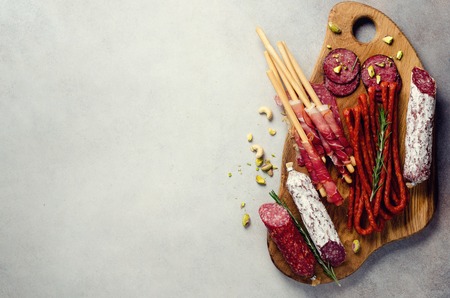 Antipasto plate with meat, olives, grissini bread sticks on grey concrete background. Top view, copy space, flat layの写真素材