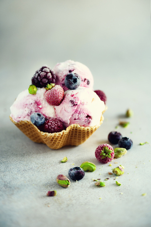 Pink ice cream with berries, strawberries, blueberries, raspberries, pistachios in waffle basket.の写真素材