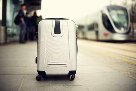 suitcase standing on railway station against city train.の写真素材