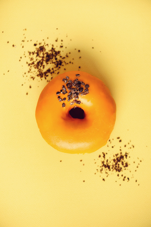 Sweet doughnut with orange glaze and chocolate on yellow background.の写真素材