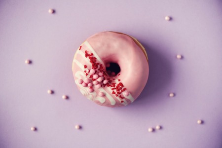 Sweet doughnut with pink icing on pastel background.の写真素材