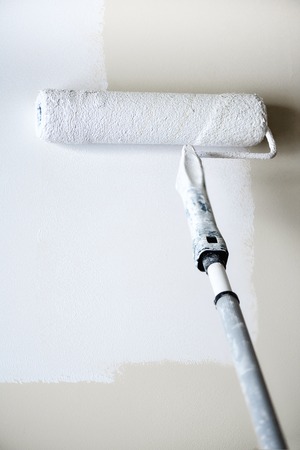 Hand painting wall with paint roller, pastel color. Appartment renovation, repair, building and home concept. Copy space, banner. Tools for painting wallsの写真素材