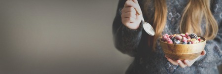 Woman hands holding oatmeal porridge with frozen berries, almonds in wooden bowl. Banner. Healthy breakfast. Clean eating, detox diet. Vegetarian, raw, vegan conceptの写真素材