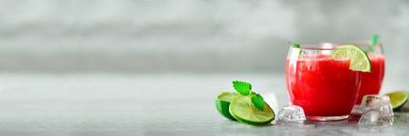 Glass of fresh watermelon juice with lime, mint, ice on light background, copy space. Banner.の写真素材