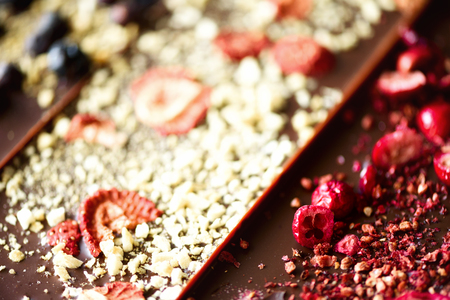 Handmade chocolate bars with dried cranberries, raspberries and pistachios, strawberries, nuts. Dark...