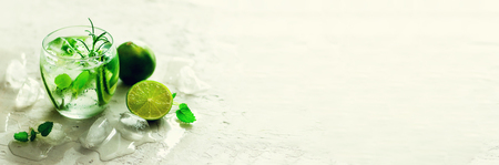 Homemade lime lemonade with cucumber, rosemary and ice, white background. Cold beverage, detox water. Copyspace. Banner.の写真素材