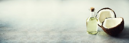 Cracked two halves of fresh organic coconut and coconut oil on grey background. Copy space. Banner.の写真素材