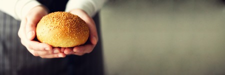Woman hands holding freshly baked bread. Bun, cookie, bakery concept, homemade food, healthy eating. Copy space. Banner.の写真素材