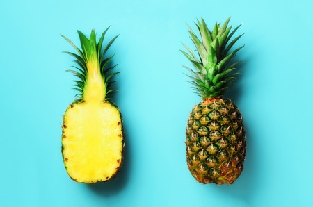 Whole pineapple and half sliced fruit on blue background. Top View. Copy Space. Bright pineapples pattern for minimal style. Pop art design, creative conceptの写真素材