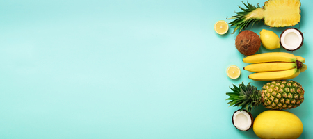 Fresh organic yellow fruits over blue background. Monochrome concept with banana, coconut, pineapple, lemon, melon. Top view. Copy space. Pop art design, creative summer design. Vegan food. Flat layの写真素材