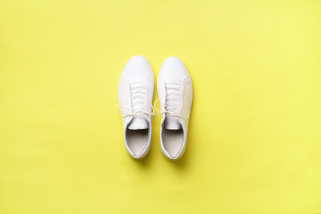 Stylish white sneakers and rope on yellow background with copy space. Top view. Minimal flat lay. Summer shoes collection. First step conceptの写真素材
